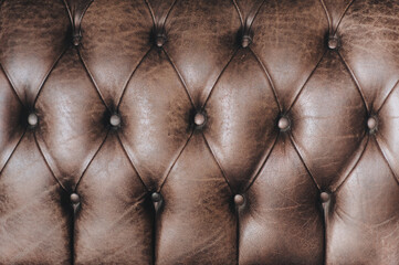 Brown leather sofa upholstery texture. The background surface is made of shiny luxury material close up. Copy space.