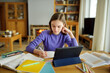 © MNStudio - Preteen schoolgirl doing her homework with digital tablet at home. Child using gadgets to study. Education and distance learning for kids. Homeschooling during quarantine.