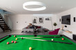 © Phillips Visuals/Stocksy - Couple relaxing in their modern apartment with pool table in foreground.