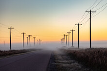 Utility Poles On Road With Fog