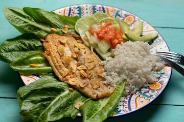 Wall Mural - Fish steak with garlic, salad and rice on turquoise background