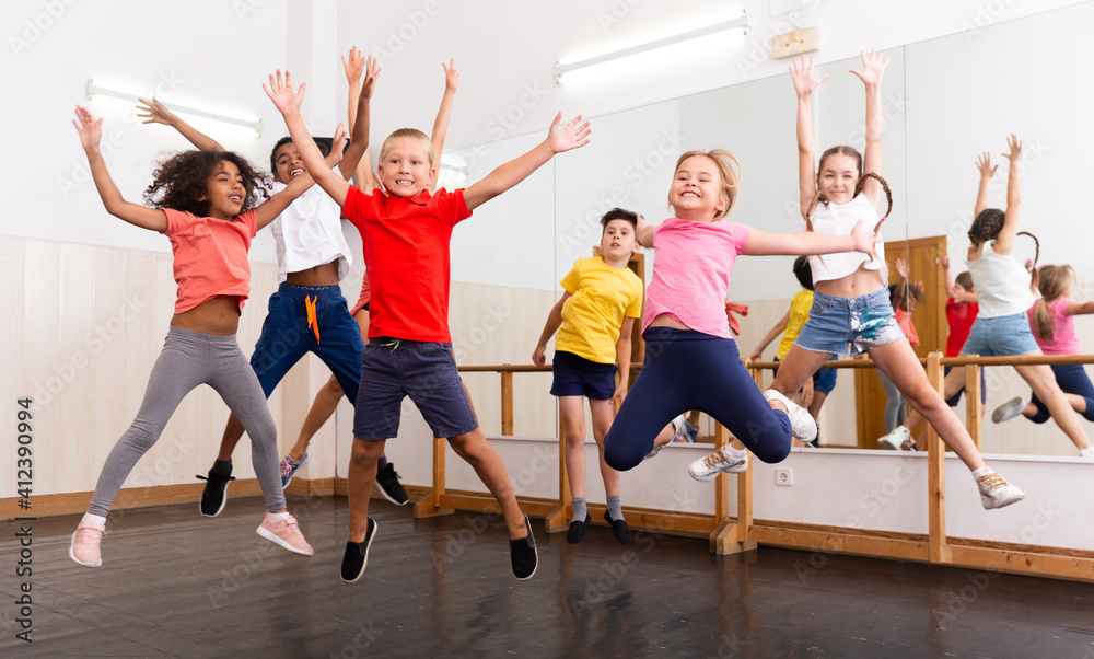 Happy kids of different nationalities and ages jumping during class in ...