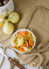 Canned vegetables in vinaigrette, with blank label and room for text. With white and rustic background and some onions.