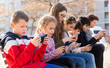 © JackF - Group of children playing with smartphones outdoors at sunny spring day