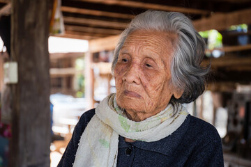 Selective focus of Older woman with short grey hair sitting at home in the countryside of Thailand, Asian older people in the rural of asia, Portrait of Asian senior women