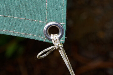 A metal eyelet in a tarpaulin keeps it securely fastened