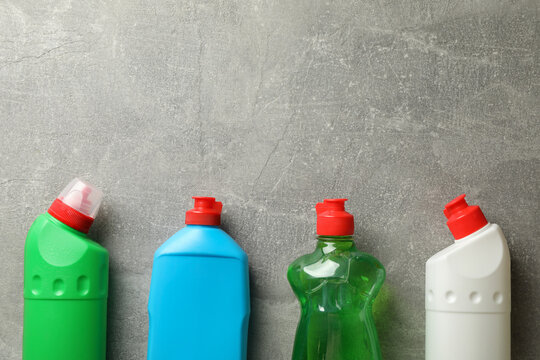 Bottles with detergent on gray background, space for text