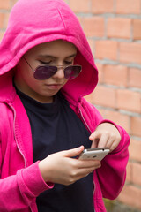 Wall Mural - young woman in sweatshirt and sunglasses using mobile phone