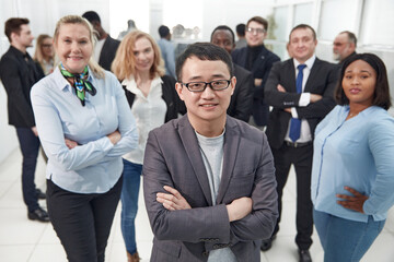 Wall Mural - young businessman standing in front of his colleagues .