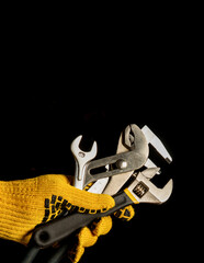 The hand in a work glove of the master holds a set of tools for repairing plumbing