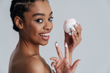 Wall Mural - Joyful shirtless african american woman showing face cream