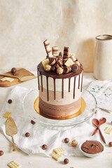 Poster - Vertical shot of chocolate ombre naked cake with sweets and chocolate drip on glass cake stand