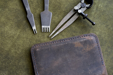 Genuine cowhide wallet with iron tools for handcraft leather. Top view, close-up.