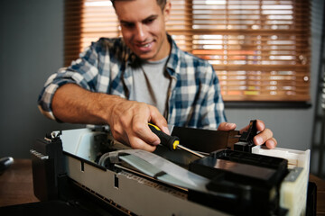 Poster - Repairman with screwdriver fixing modern printer in office, focus on hand