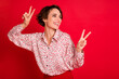 © deagreez - Portrait of lovely cute cheerful brown-haired girl showing v-sign dancing having fun isolated over bright red color background