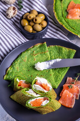 Canvas Print - pancakes or crepes with spinach, salmon and cream cheese. green food. Trendy vegetarian food. vertical image