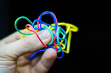 Cropped Hand Holding Colorful Rubber Bands Against Black Background