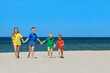 © Trutta - Two girls and two boys in colorful t-shirts walking on a sandy beach