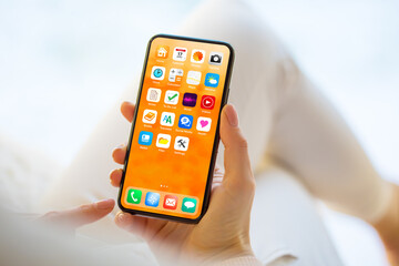 woman using mobile phone with home screen opened showing different everyday app icons
