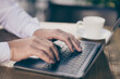 © deagreez - Cropped photo of hands type write laptop behind table businessman work programmer in city center cafe