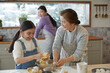 © stciel - Happy adorable little child girl in apron enjoying cooking homemade pastry together with family at home.