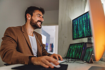 Young handsome programmer dressed business casual sitting in his office and working on important project . Quarantine during corona virus concept.