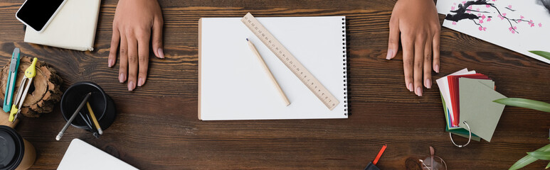 Canvas Print - top view of hands of interior designer near sketchbook, pencil and ruler on desk, banner