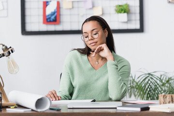 Canvas Print - thoughtful african american interior designer sitting at desk at home studio, blurred foreground