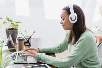 Canvas Print - side view of young african american interior designer typing on laptop at home