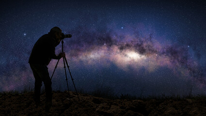 silhouette of a photographer shooting the milky way in a starry night sky.