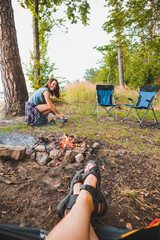 Wall Mural - couple resting near bonfire. woman cooking outdoors on fire