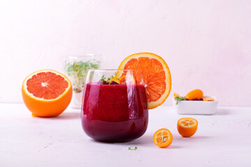 Smoothie with beet root, berries and blood orange topped with microgreen in a glass on white