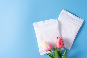 Wall Mural - Sanitary pad, Sanitary napkin with tulip flower on blue background. Menstruation, Feminine hygiene, top view.