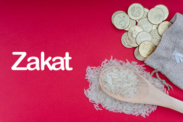 Wall Mural - ZAKAT words with Coins and Rice on red background. Zakat concept. Zakat is a form of alm-giving as a religious obligation