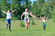 © alexmak - Happy mother having fun jumping with her daughters on green grass