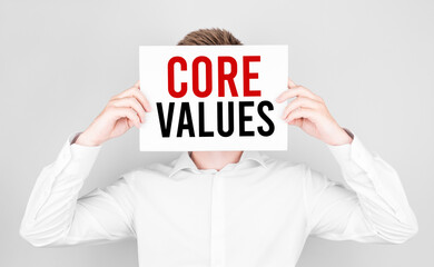 Poster - man covers his face with a white paper with text core values