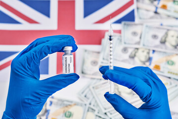 Researcher hand in blue gloves holding coronavirus, covid-19 vaccine against background of flag of England and money disease preparing for human clinical trials vaccination shot, medicine concept.