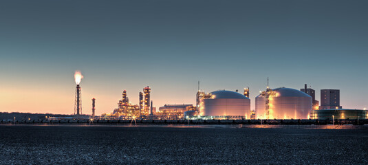 Fertilizer plant in an agricultural landscape at sunset. Railroad tanker cars stretched across the image. 