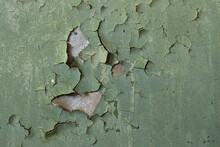 Green Peeling Paint On The Wall. Old Concrete Wall With Cracked Flaking Paint. Weathered Rough Painted Surface With Patterns Of Cracks And Peeling. High Resolution Texture For Background And Design.
