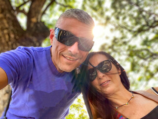 Poster - happy couple smiling in front of the camera. upward view with sun light through the trees