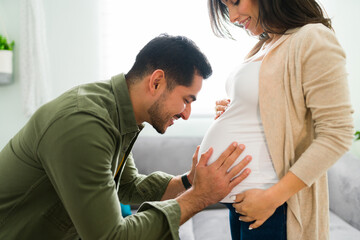 Handsome man putting her face close to her wife's belly