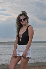 beautiful girl at the sea in a swimsuit and glasses sunbathes on the beach