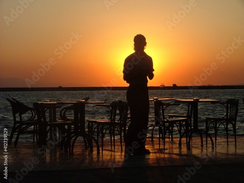 Silhouette Man Standing At Cafe By Sea Against Sky During Sunset
