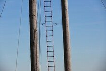 Low Angle View Of Wooden Poles And Ladder Against Clear Blue Sky