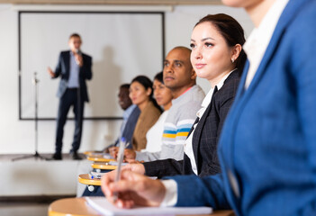 Sticker - Young focused woman sitting and listening to speaker at business conference