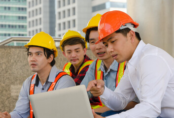 Engineering team working together on building site and using laptop for project progress.