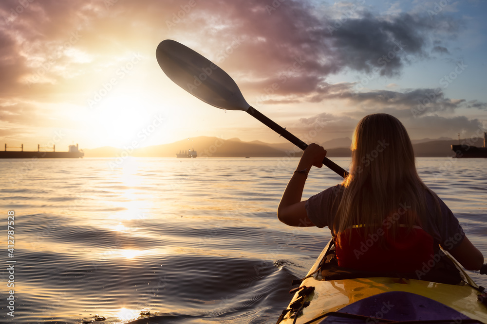 Woman on a sea kayak is paddling in the ocean during a colorful and vibrant sunset. Taken in Jericho, Vancouver, British Columbia, Canada. Concept: Adventure, Holiday, Vacation, Lifestyle, Freedom - obrazy, fototapety, plakaty 