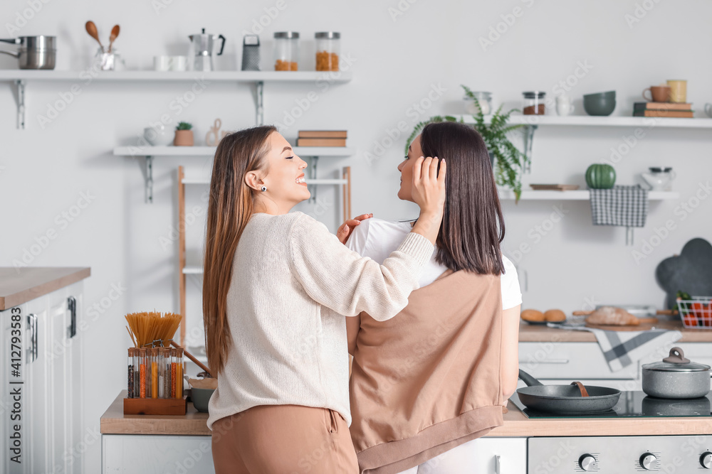 Young lesbian couple cooking dinner in kitchen