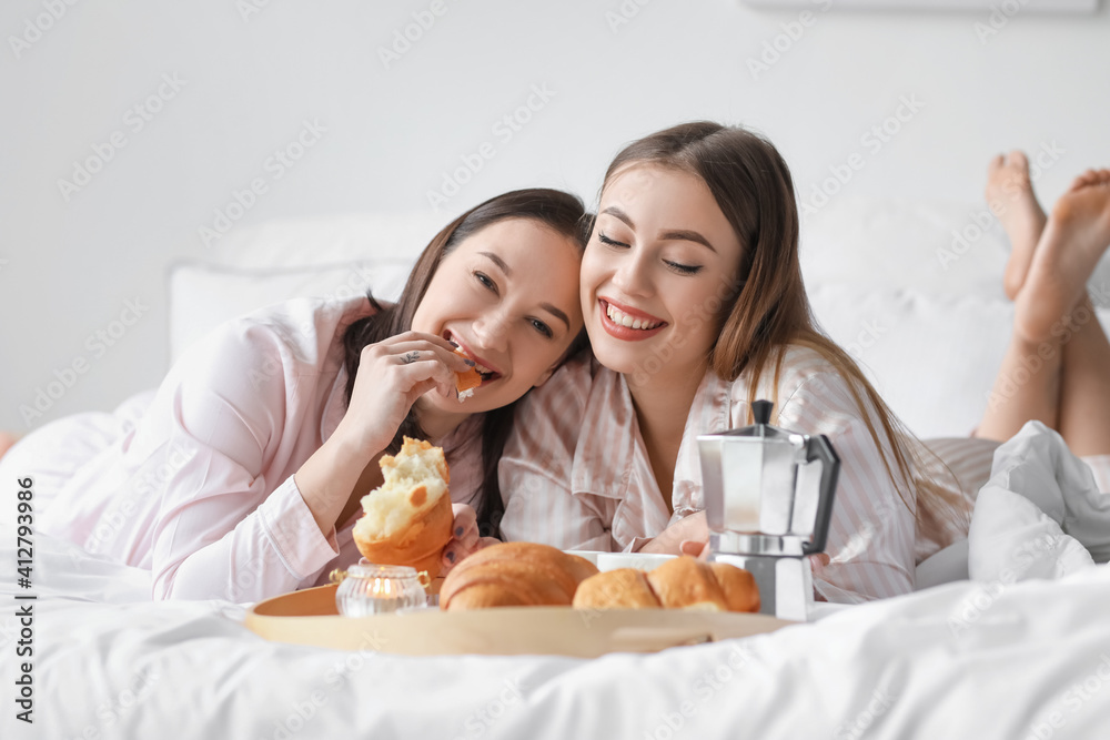 Young lesbian couple having breakfast in bed