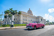 vintage American retro car carconvertible rides on an asphalt road in front of the Capitol in old town Havana. Tourist taxi cabriolet.